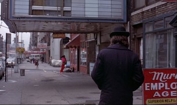 Movie still from “Heavy Traffic” (1973), directed by Ralph Bakshi – A man wearing a black hat and a black coat; Wide shot, Over the shoulder angle