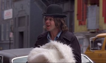 Movie still from “Heavy Traffic” (1973), directed by Ralph Bakshi – A man in a black hat is holding a white furry hat; Medium shot, Low angle