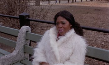 Movie still from “Heavy Traffic” (1973), directed by Ralph Bakshi – A woman sitting on top of a wooden park bench; Medium shot, High angle