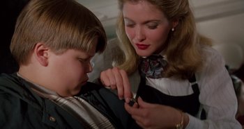 Movie still from “Heavyweights” (1995), directed by Steven Brill – A woman is helping a young boy fix a tie; Close Up shot, Overhead angle