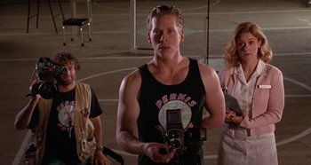 Movie still from “Heavyweights” (1995), directed by Steven Brill – A man holding a camera in front of two other people; Medium shot, Low angle