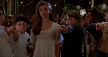 Movie still from “Heavyweights” (1995), directed by Steven Brill – A young boy pointing at a young girl in front of a crowd; Medium shot, Over the shoulder angle