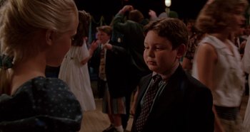Movie still from “Heavyweights” (1995), directed by Steven Brill – A boy in a suit and tie standing in front of a crowd; Medium shot, Over the shoulder angle