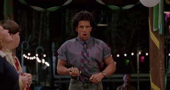 Movie still from “Heavyweights” (1995), directed by Steven Brill – A man in a purple shirt holding a knife in his hand; Medium shot, Low angle