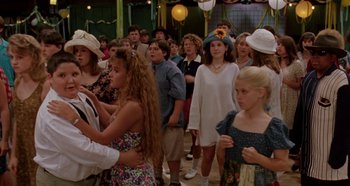 Movie still from “Heavyweights” (1995), directed by Steven Brill – A group of people standing around each other in front of a crowd; Medium shot, Over the shoulder angle