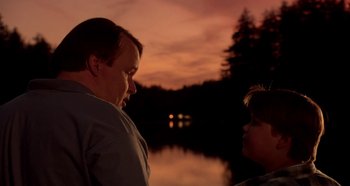 Movie still from “Heavyweights” (1995), directed by Steven Brill – A man standing next to a woman near a body of water; Medium shot, Over the shoulder angle