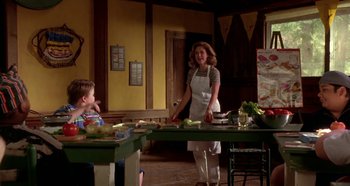 Movie still from “Heavyweights” (1995), directed by Steven Brill – A woman and a child preparing food in a kitchen; Medium shot, Over the shoulder angle