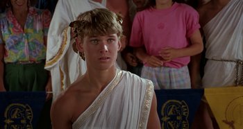 Movie still from “Heavyweights” (1995), directed by Steven Brill – A man in a toga is standing in front of other people; Close Up shot, Over the shoulder angle