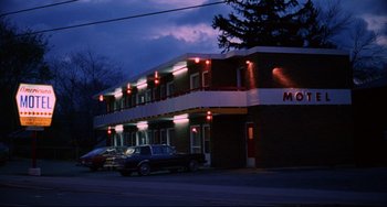 Movie still from “Hedwig and the Angry Inch” (2001), directed by John Cameron Mitchell – A car parked in front of a building at night; Extreme Wide shot, Low angle