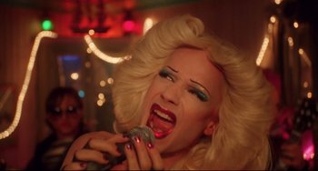 Movie still from “Hedwig and the Angry Inch” (2001), directed by John Cameron Mitchell – A drag queen is singing into a microphone; Close Up shot, Overhead angle