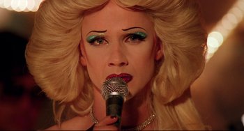 Movie still from “Hedwig and the Angry Inch” (2001), directed by John Cameron Mitchell – A person with blonde hair and a microphone; Close Up shot, Overhead angle