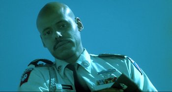 Movie still from “Hedwig and the Angry Inch” (2001), directed by John Cameron Mitchell – A man in a uniform is looking at a book; Close Up shot, Low angle