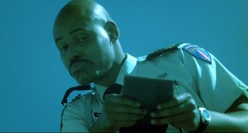 Movie still from “Hedwig and the Angry Inch” (2001), directed by John Cameron Mitchell – A police officer looking down at a piece of paper; Close Up shot, Low angle