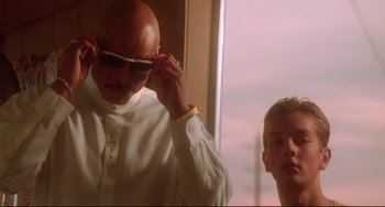 Movie still from “Hedwig and the Angry Inch” (2001), directed by John Cameron Mitchell – A man adjusts a pair of sunglasses in front of another man; Medium shot, Low angle