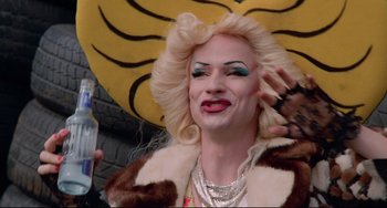 Movie still from “Hedwig and the Angry Inch” (2001), directed by John Cameron Mitchell – A woman with blonde hair and blue eyes wearing a fur coat; Close Up shot, Over the shoulder angle
