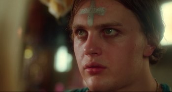 Movie still from “Hedwig and the Angry Inch” (2001), directed by John Cameron Mitchell – A person with a cross on their forehead; Close Up shot, Over the shoulder angle