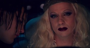 Movie still from “Hedwig and the Angry Inch” (2001), directed by John Cameron Mitchell – A woman with blonde hair and a purple lipstick; Close Up shot, Over the shoulder angle