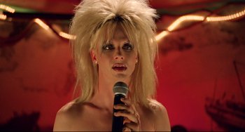 Movie still from “Hedwig and the Angry Inch” (2001), directed by John Cameron Mitchell – A woman with a blonde wig is holding a microphone in front of her face; Close Up shot, Low angle