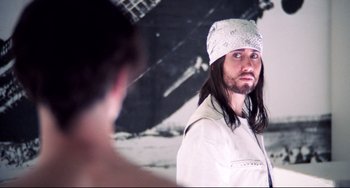 Movie still from “Hedwig and the Angry Inch” (2001), directed by John Cameron Mitchell – A man with long hair and a bandanna on his head; Close Up shot, Over the shoulder angle