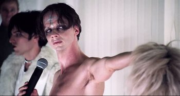 Movie still from “Hedwig and the Angry Inch” (2001), directed by John Cameron Mitchell – A shirtless man with a microphone in front of him; Close Up shot, Low angle