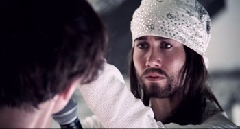 Movie still from “Hedwig and the Angry Inch” (2001), directed by John Cameron Mitchell – A man with long white hair and a white hat; Close Up shot, Over the shoulder angle