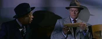 Movie still from “Hell and High Water” (1954), directed by Samuel Fuller – A man in a hat and a man in a suit and tie; Close Up shot, Over the shoulder angle