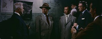 Movie still from “Hell and High Water” (1954), directed by Samuel Fuller – A man in a suit and hat standing next to another man in a suit and hat; Medium shot, Low angle