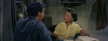 Movie still from “Hell and High Water” (1954), directed by Samuel Fuller – A woman sitting at a table talking to a man; Medium shot, Over the shoulder angle