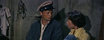 Movie still from “Hell and High Water” (1954), directed by Samuel Fuller – A man wearing a hat and jacket talking to a woman; Close Up shot, High angle
