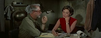Movie still from “Hell and High Water” (1954), directed by Samuel Fuller – An older man and a young woman sitting at a table; Medium shot, High angle