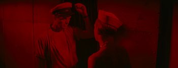 Movie still from “Hell and High Water” (1954), directed by Samuel Fuller – A man and a woman in a red room; Medium shot, High angle