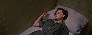 Movie still from “Hell and High Water” (1954), directed by Samuel Fuller – A woman laying on the ground smoking a cigarette; Medium shot, High angle