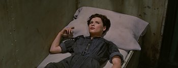 Movie still from “Hell and High Water” (1954), directed by Samuel Fuller – A woman laying on the ground smoking a cigarette; Medium shot, Overhead angle