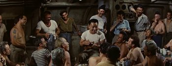 Movie still from “Hell and High Water” (1954), directed by Samuel Fuller – A group of people gathered around a man holding a ukulele; Medium shot, High angle