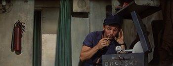 Movie still from “Hell and High Water” (1954), directed by Samuel Fuller – A man sitting in front of a microphone on a phone; Medium shot, High angle