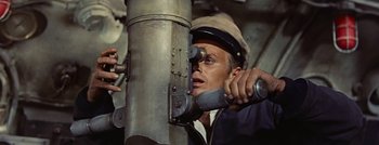 Movie still from “Hell and High Water” (1954), directed by Samuel Fuller – A man in a hat looking through a telescope; Close Up shot, Overhead angle