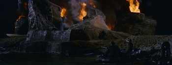 Movie still from “Hell and High Water” (1954), directed by Samuel Fuller – A man sitting on the ground in front of a fire; Extreme Wide shot, High angle