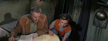 Movie still from “Hell and High Water” (1954), directed by Samuel Fuller – An older man and a young boy looking at papers on a table; Medium shot, High angle