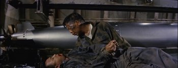 Movie still from “Hell and High Water” (1954), directed by Samuel Fuller – A man in military fatigues is holding a man in military fatigues; Medium shot, High angle