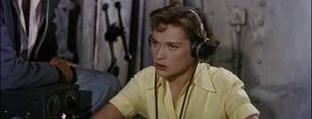 Movie still from “Hell and High Water” (1954), directed by Samuel Fuller – A woman wearing headphones and looking at the camera; Close Up shot, High angle