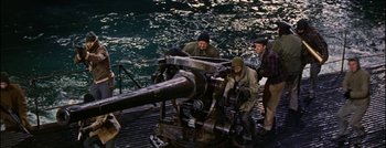 Movie still from “Hell and High Water” (1954), directed by Samuel Fuller – A group of men standing on top of a boat next to a cannon; Wide shot, High angle