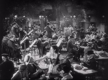 Movie still from “Hell's Angels” (1930), directed by Edmund Goulding – An old black and white photo of people sitting at tables with musical instruments; Wide shot, High angle
