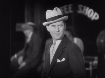 Movie still from “Hell's Angels” (1930), directed by Edmund Goulding – A black and white photo of a man in a suit and hat; Medium shot, Low angle