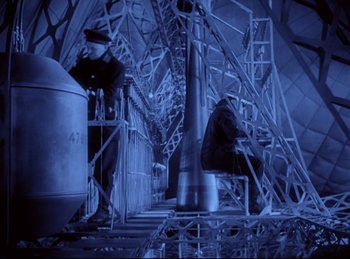 Movie still from “Hell's Angels” (1930), directed by Edmund Goulding – A man standing next to a large metal structure; Wide shot, High angle
