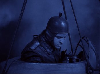 Movie still from “Hell's Angels” (1930), directed by Edmund Goulding – A man wearing a helmet is sitting in a bucket; Medium shot, High angle