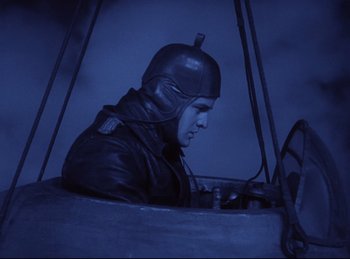Movie still from “Hell's Angels” (1930), directed by Edmund Goulding – A man wearing a helmet sitting inside of an airplane; Medium shot, High angle