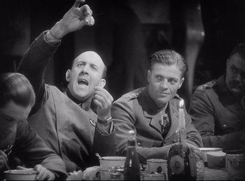 Movie still from “Hell's Angels” (1930), directed by Edmund Goulding – Two men sitting at a table in front of each other; Medium shot, Low angle