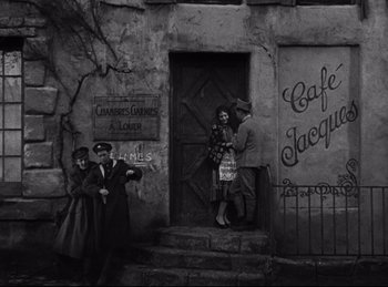 Movie still from “Hell's Angels” (1930), directed by Edmund Goulding – A black and white photo of a group of people standing in front of a building; Wide shot, High angle