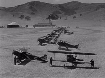 Movie still from “Hell's Angels” (1930), directed by Edmund Goulding – A group of airplanes parked on top of a dirt field; Extreme Wide shot, High angle