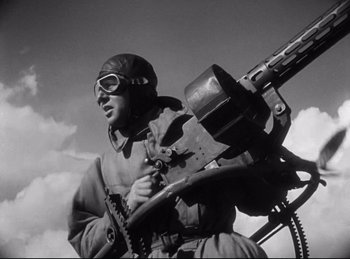 Movie still from “Hell's Angels” (1930), directed by Edmund Goulding – An old photo of a man holding a machine gun; Medium shot, Low angle